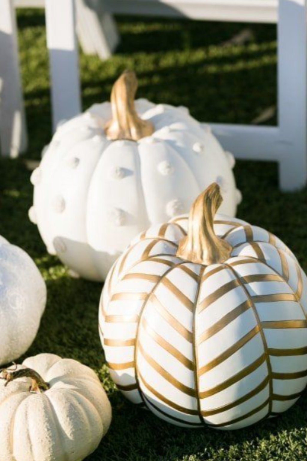 Chevron and dotted white pumpkins placed outdoors for modern fall curb appeal.
