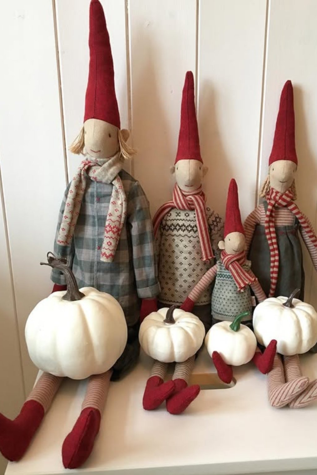 Cute gnome dolls paired with white pumpkins for a whimsical holiday shelf display.