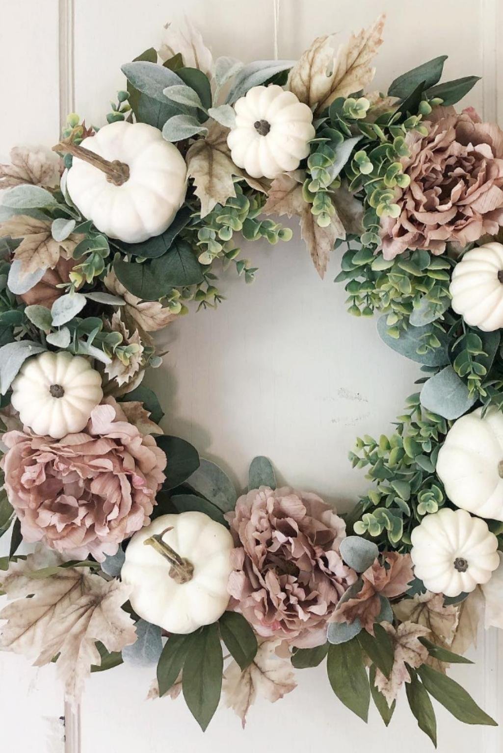 White pumpkins and muted florals arranged into a decorative fall wreath.