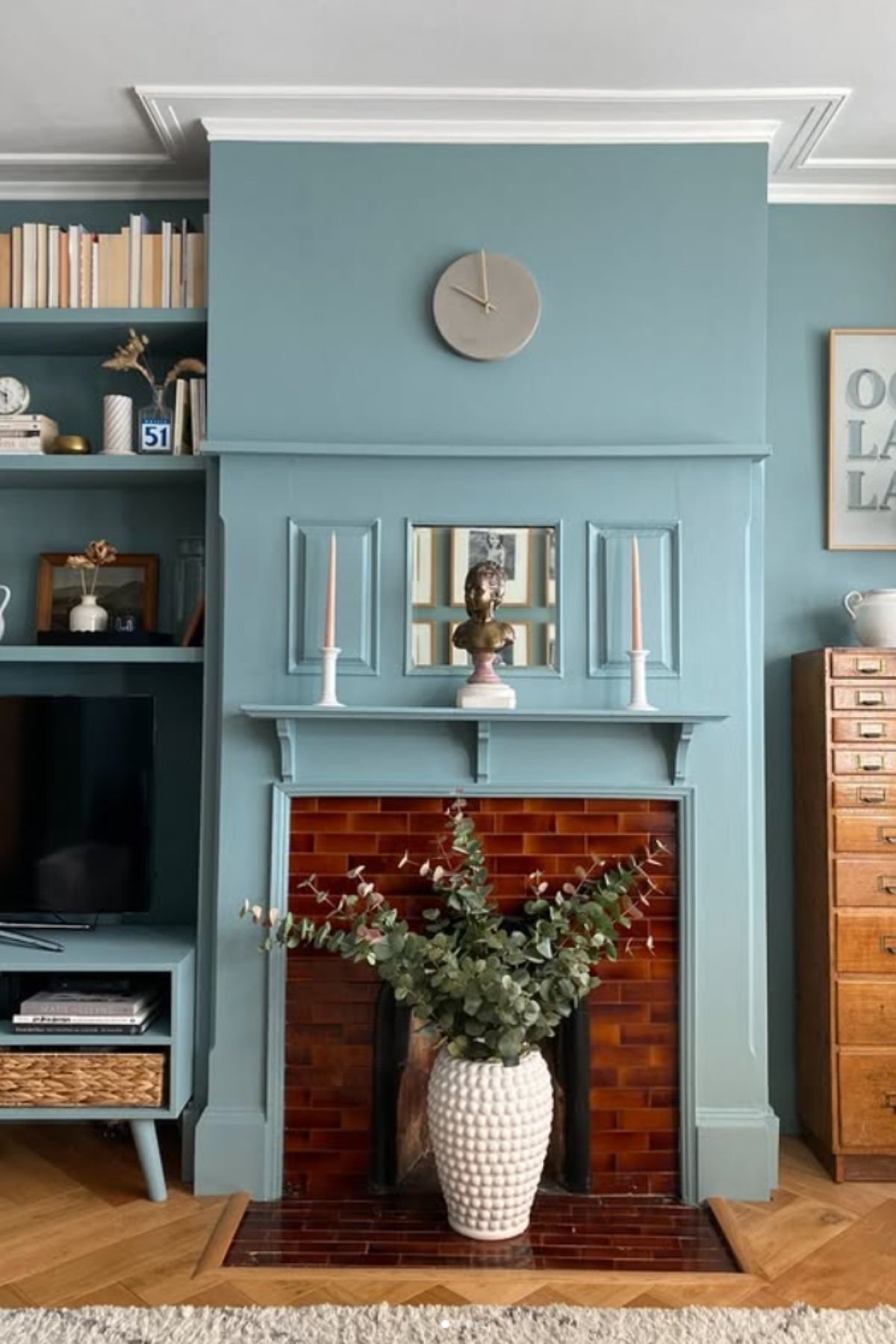 Muted light blue wall paint color framing a red-brown tiled fireplace.