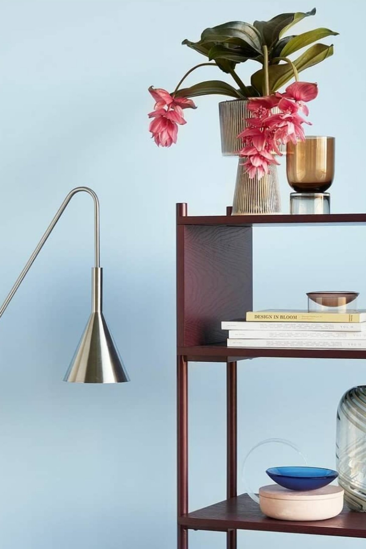 Minimalist shelving and pink flowers against light blue wall paint color.