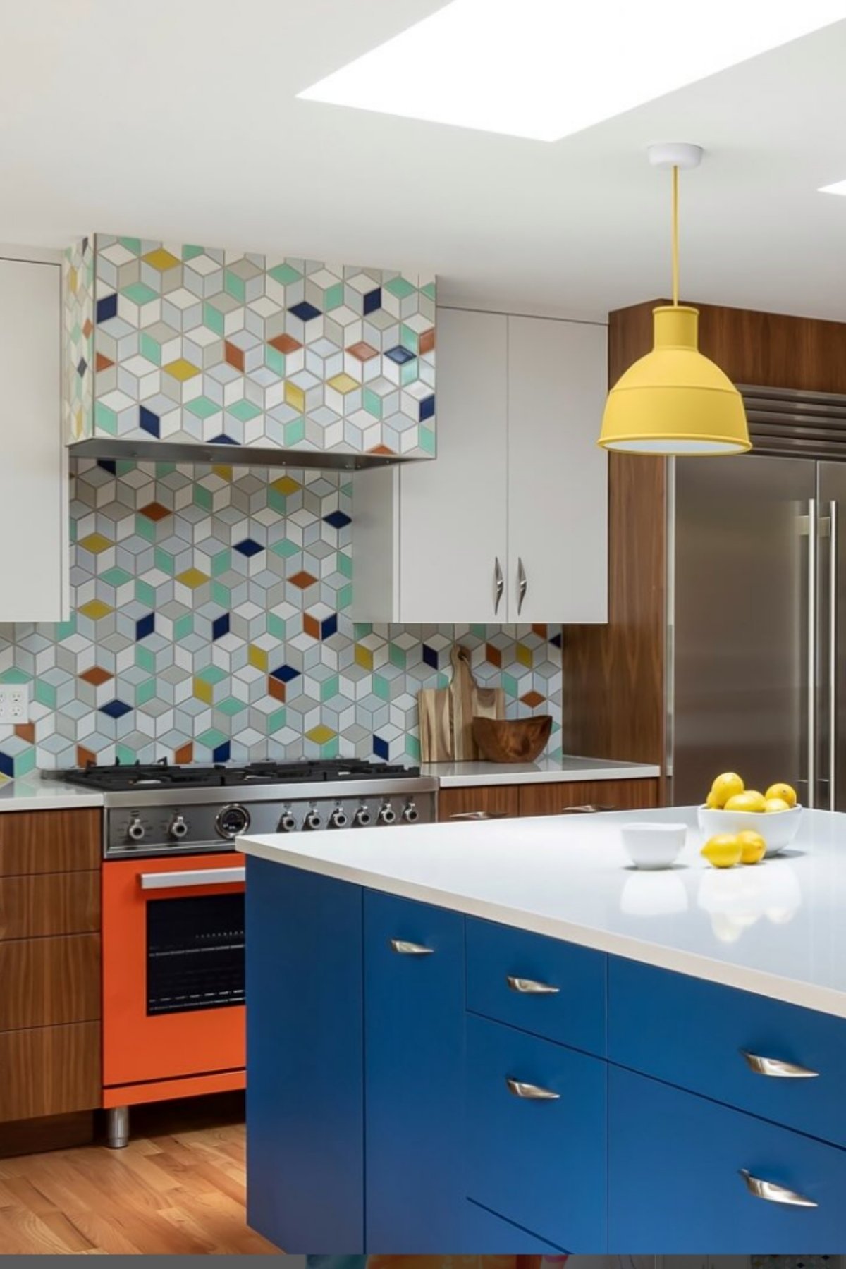 Blue cabinets, orange appliances, and patterned backsplash in modern kitchen.