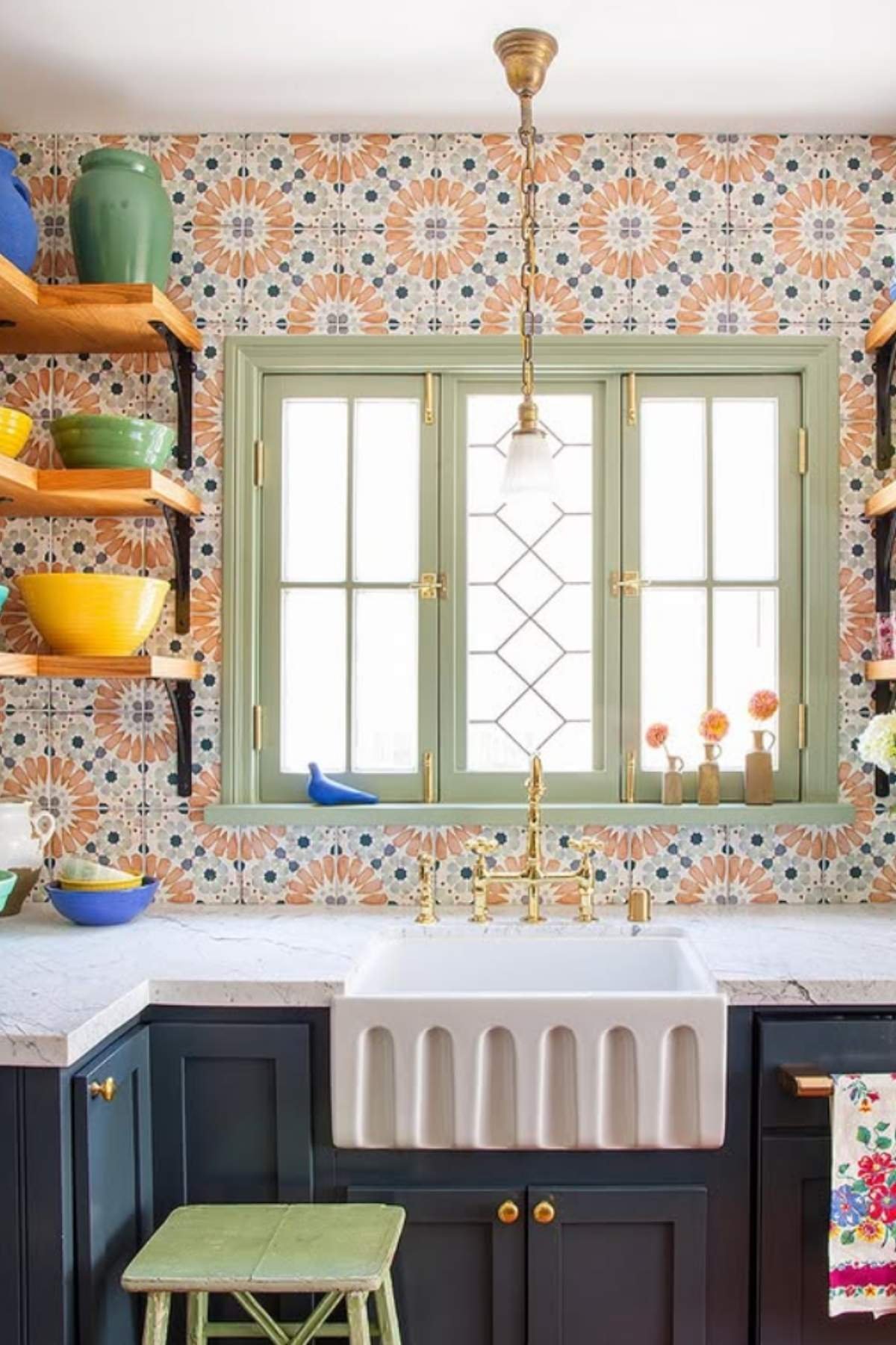 Farmhouse sink with floral tile backsplash and green trim.