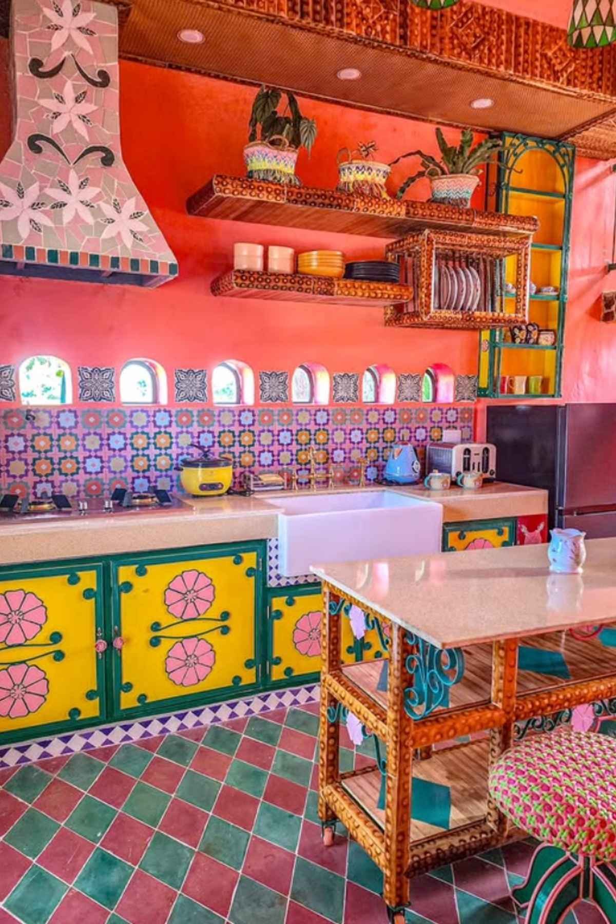 Red and yellow fiesta-inspired kitchen with patterned tiles and wooden furniture.
