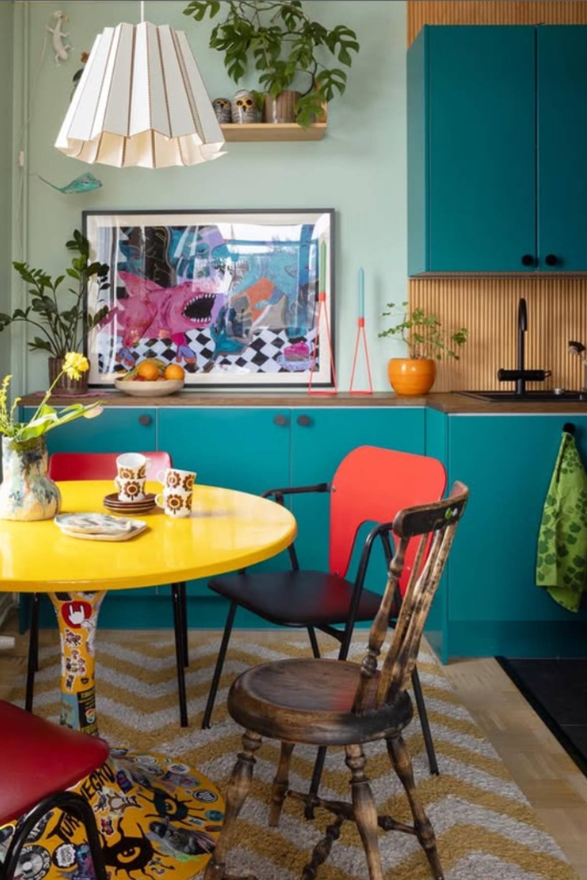 Teal cabinet kitchen with yellow table and vintage chairs.