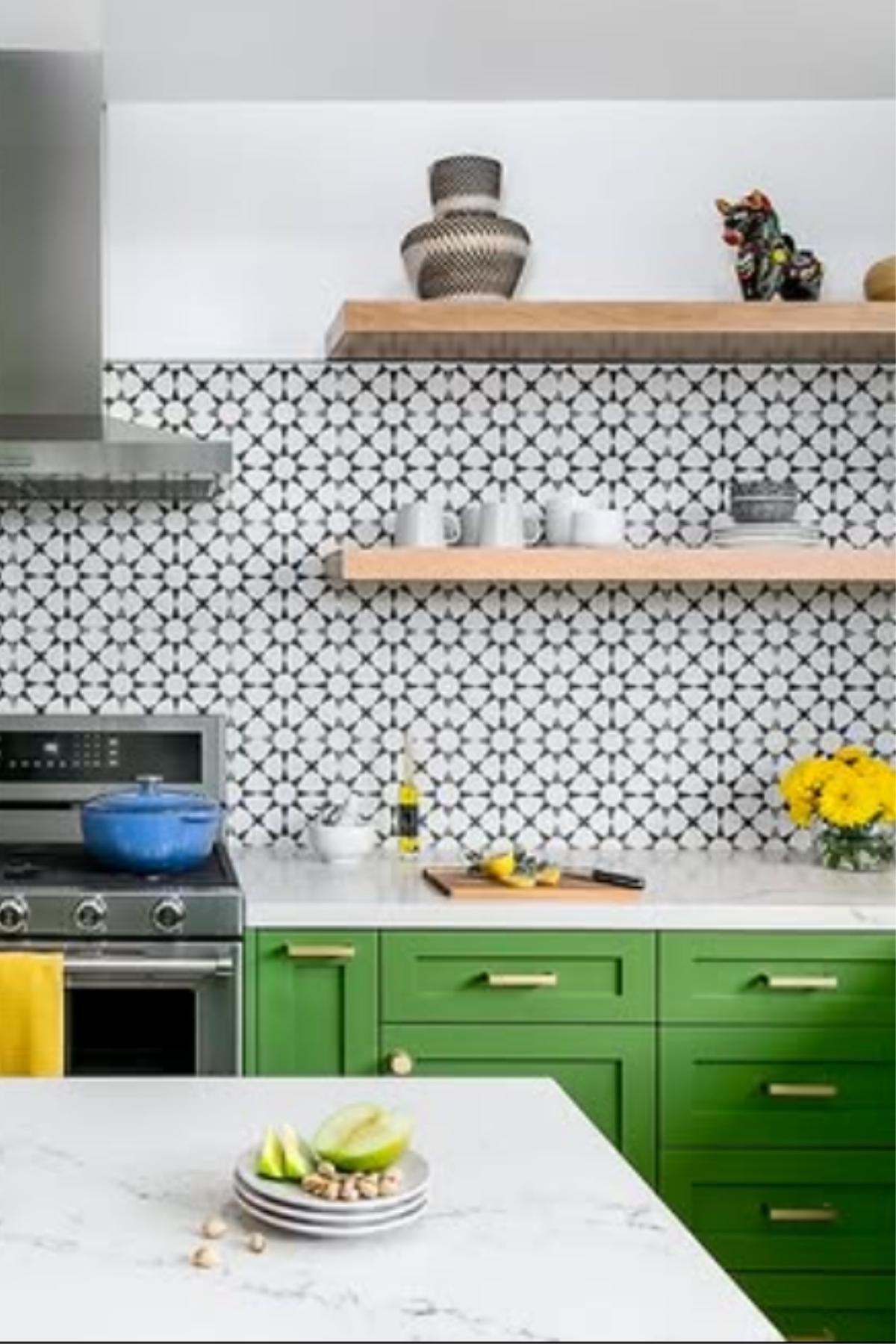 Black-and-white patterned backsplash with green kitchen cabinets.