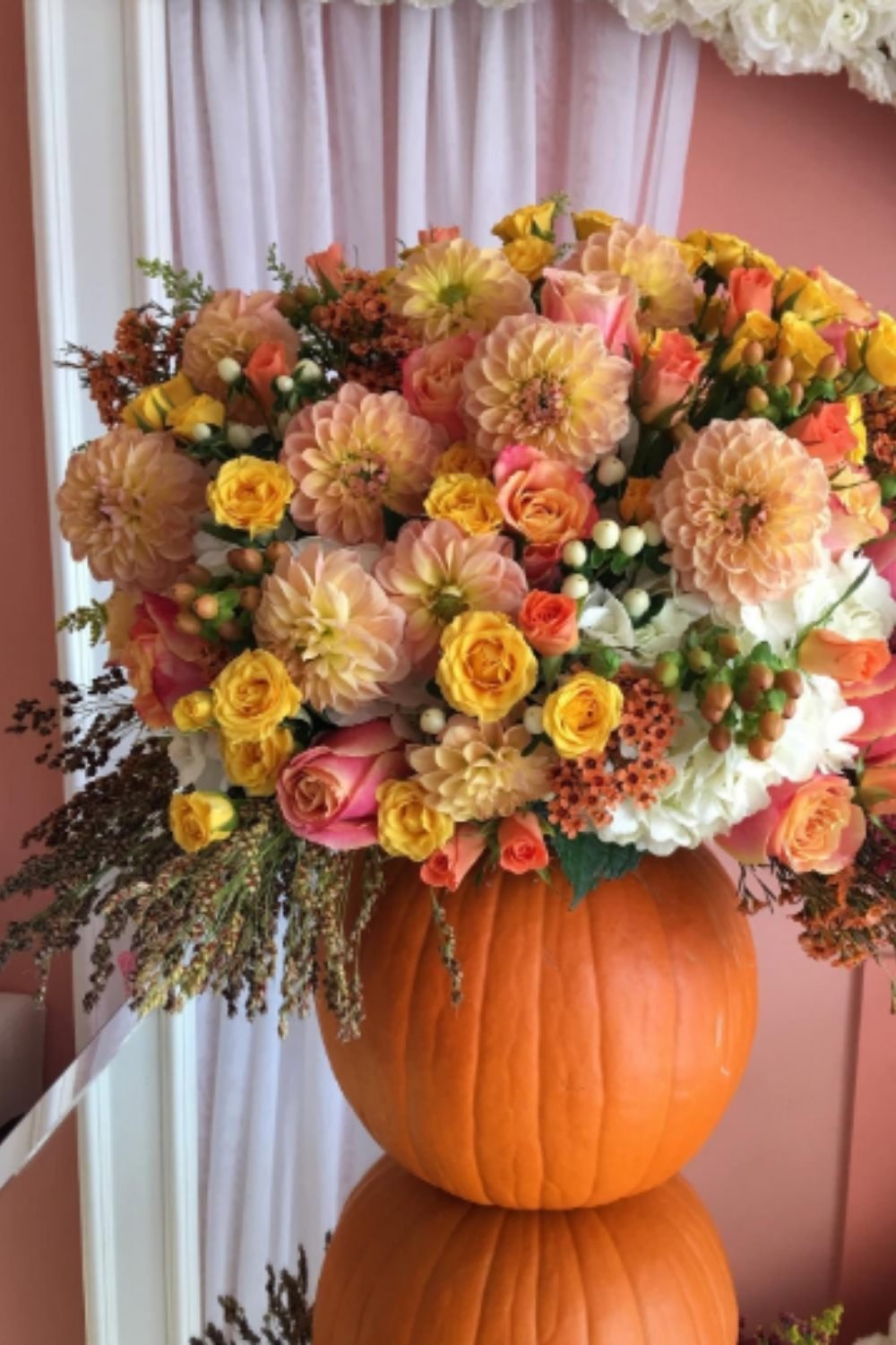 Lush autumn pumpkin floral arrangements with dahlias, mums, and roses in warm seasonal colors.