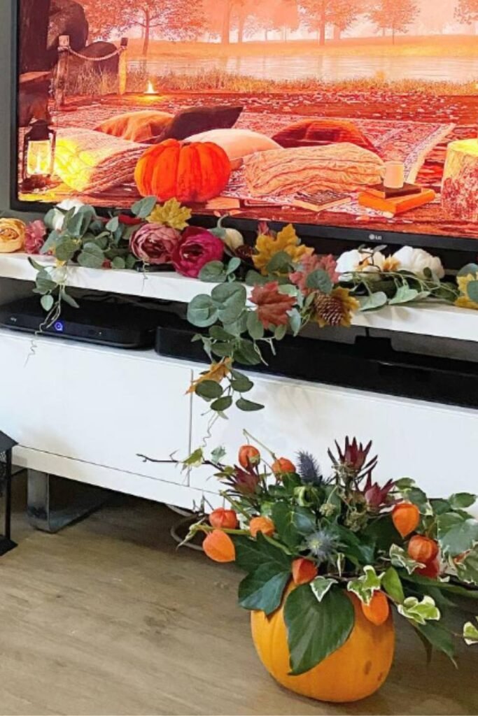 Seasonal pumpkin floral arrangements with mums, roses, and trailing greenery styled on a whole pumpkin.