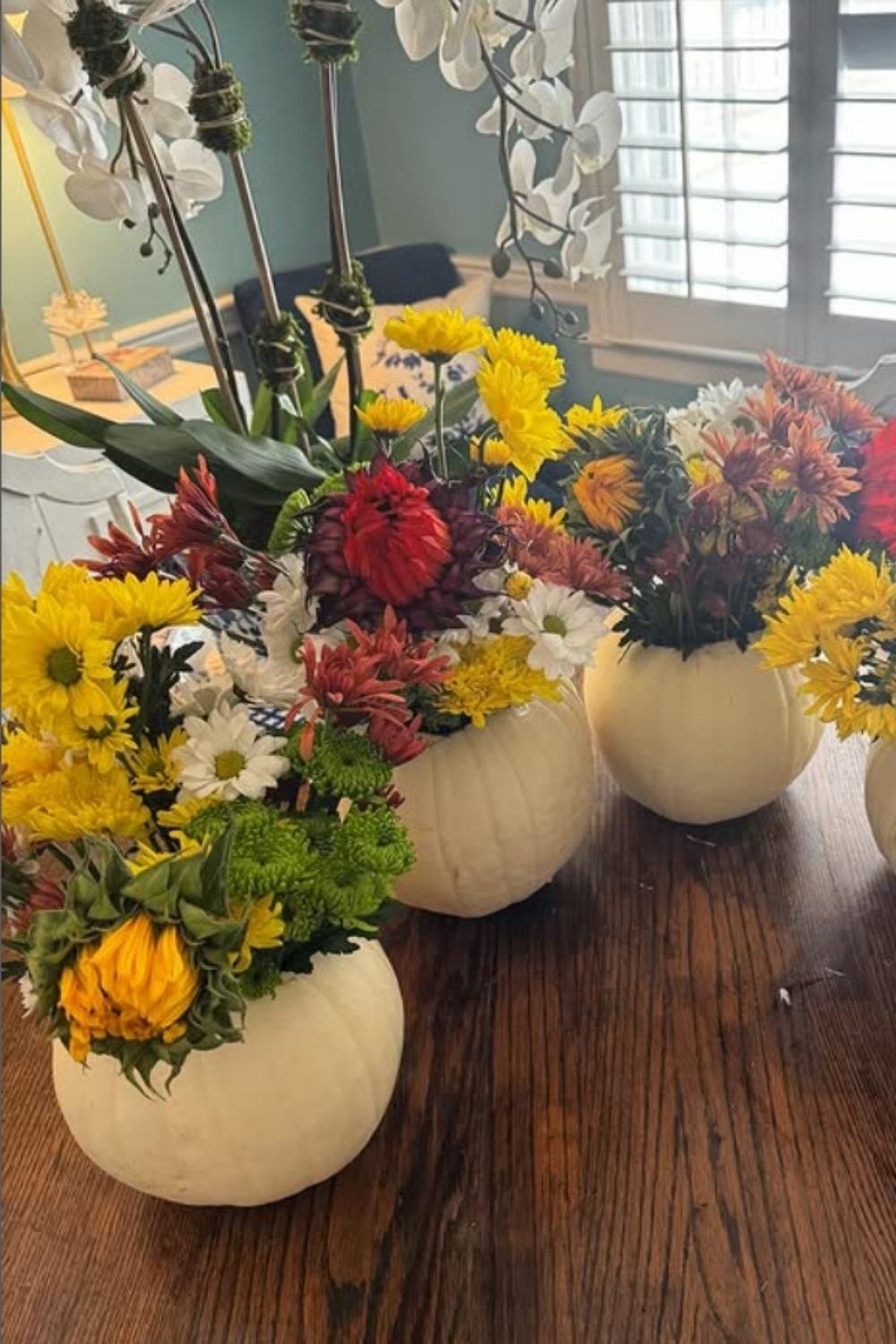 Mini white pumpkin floral arrangements clustered together with chrysanthemums and zinnias for a casual centerpiece