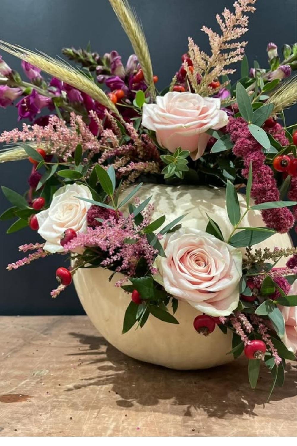 Elegant rose pumpkin floral arrangements in a white pumpkin with roses, astilbe, and greenery.