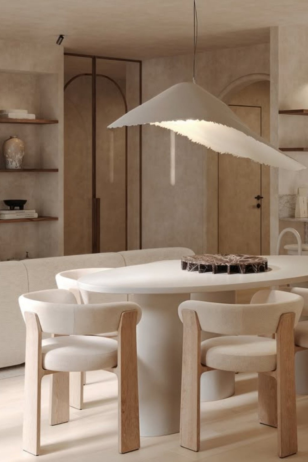 Minimal dining area with white table, matching chairs, and sculptural pendant.