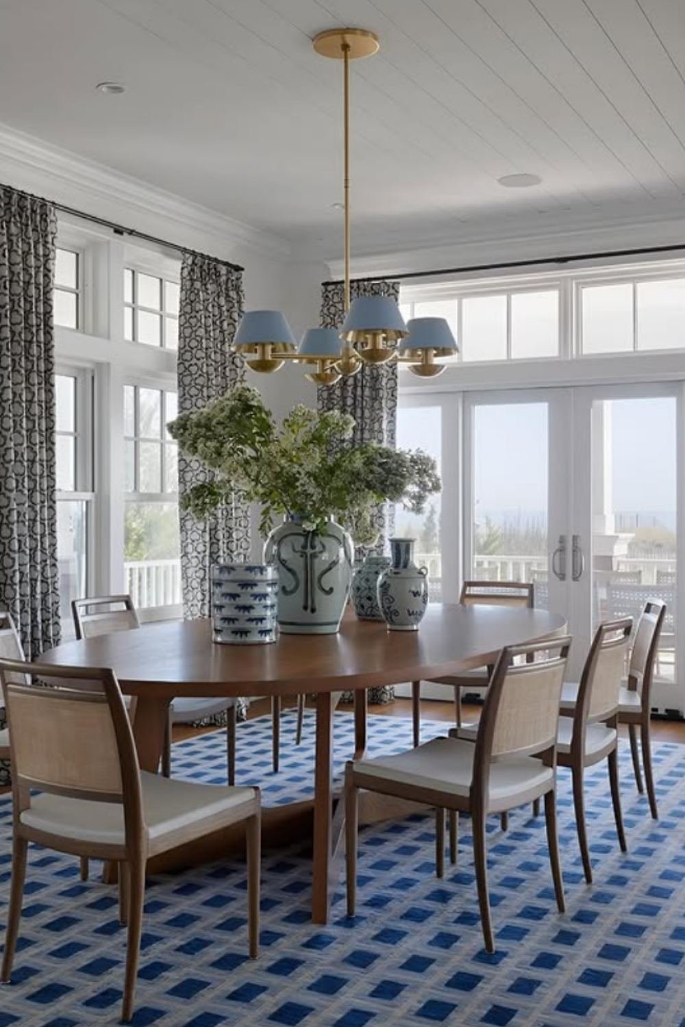Coastal-inspired space with blue patterned rug and light wood furniture.
