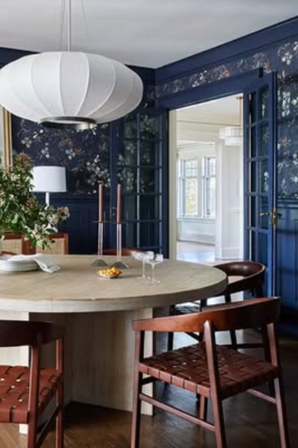 Artistic dining area with floral navy wallpaper and round wooden table.