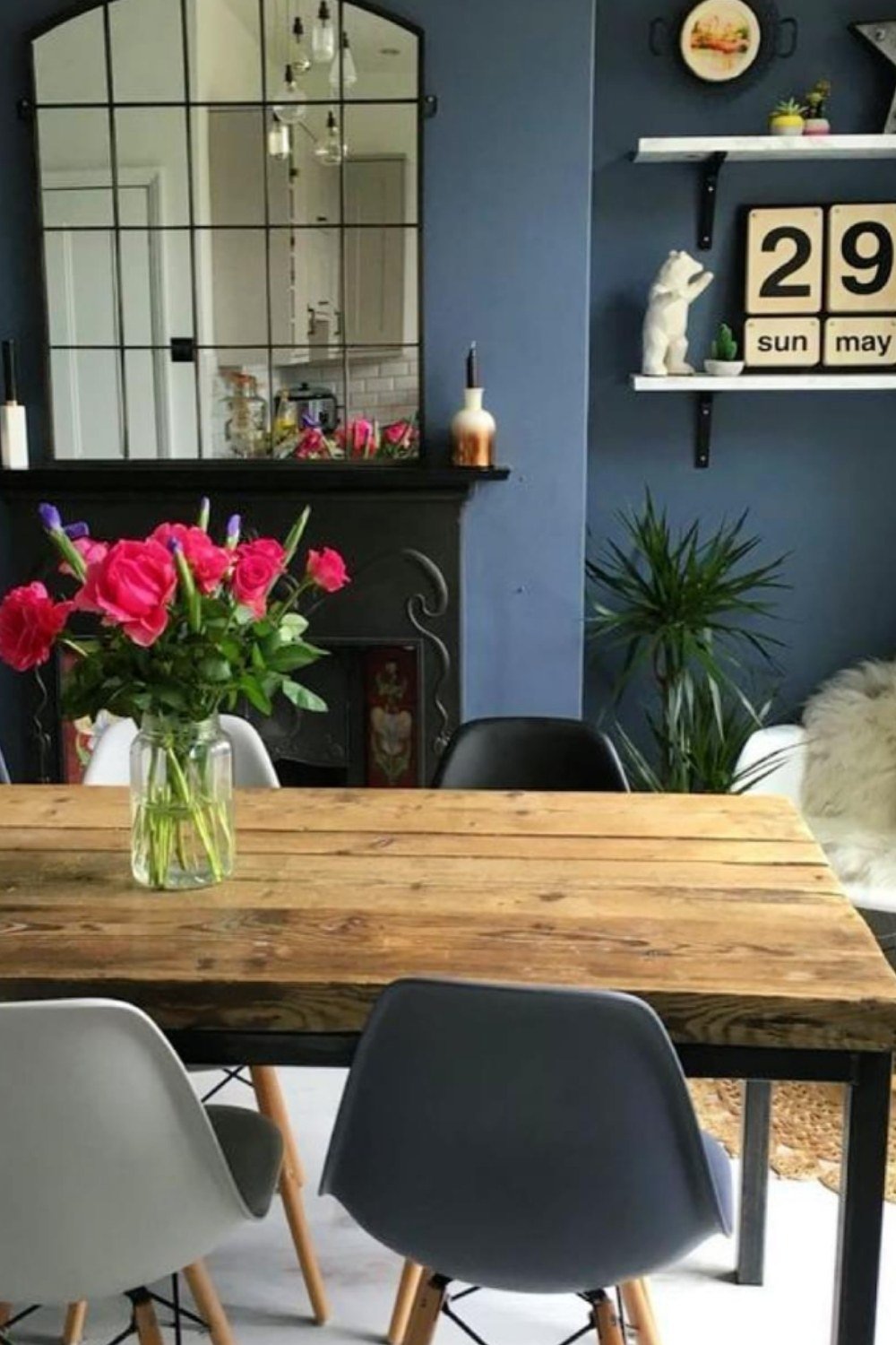 Casual dining space with rustic wooden table, blue walls, and mismatched chairs.