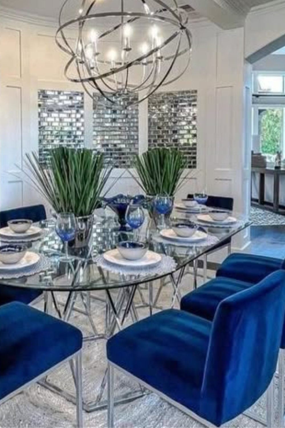 Eclectic blue dining room with rattan chairs, wooden table, and globe chandelier.