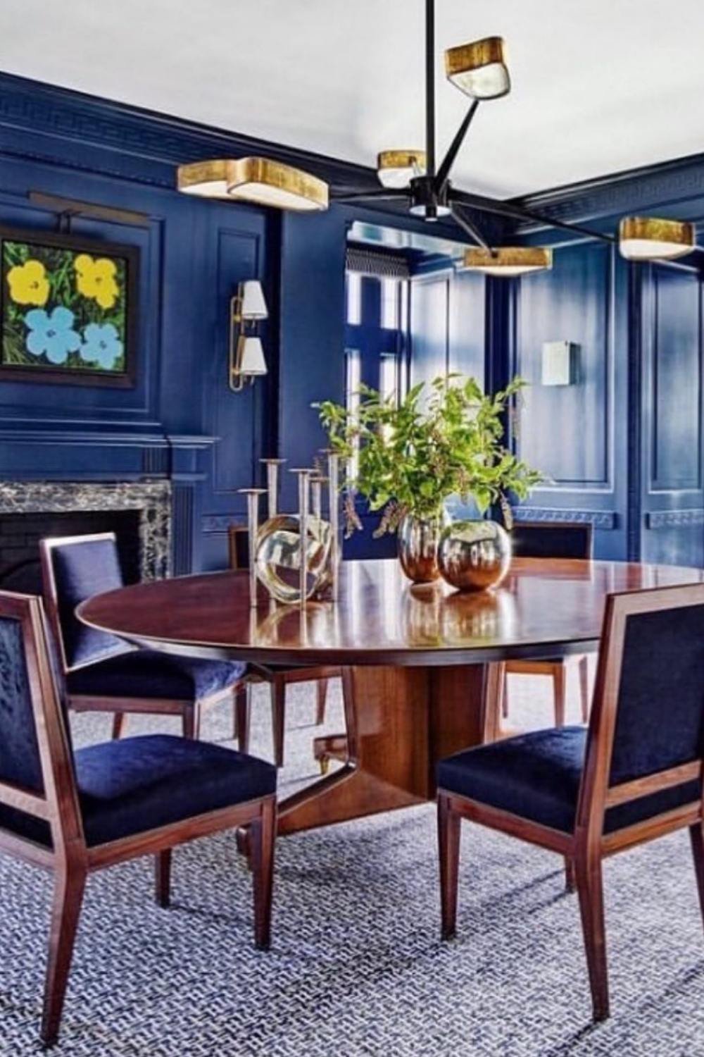Mid-century inspired blue dining room with navy walls, wooden table, and brass lighting.
