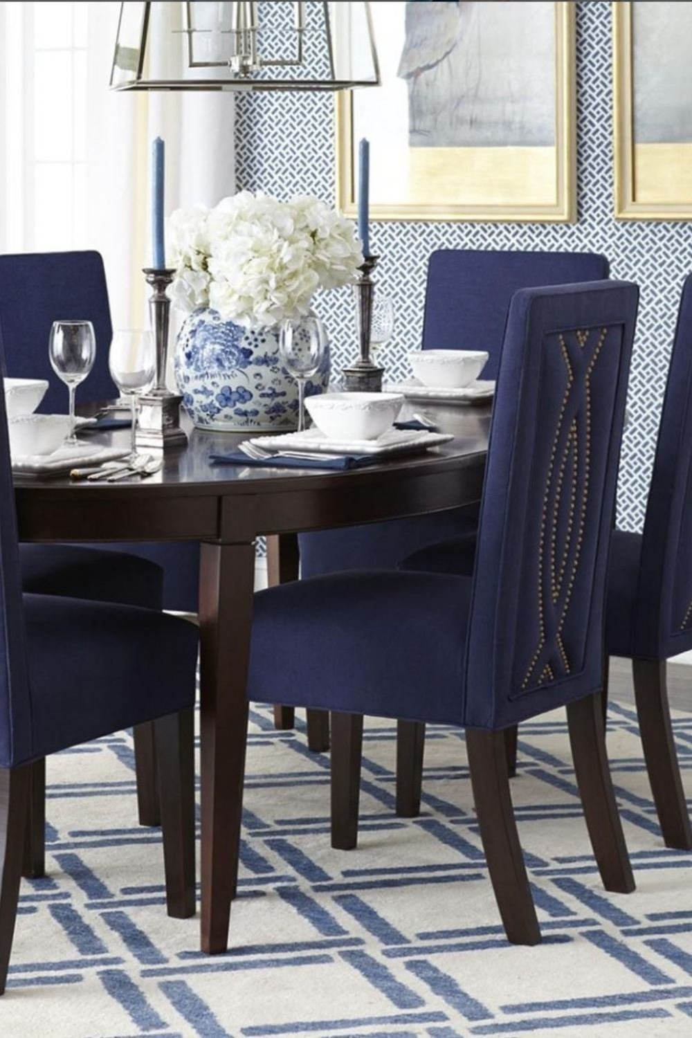 Formal blue dining room with deep blue upholstered chairs and a patterned rug.