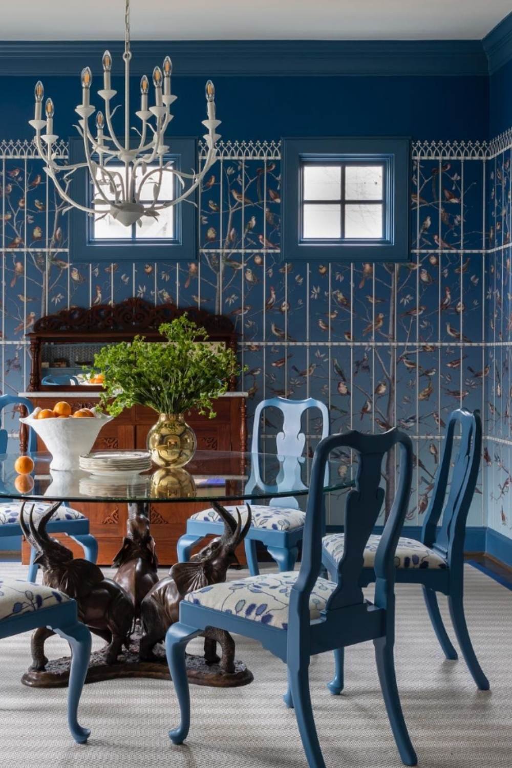 blue patterned wallpaper, painted chairs, and chandelier.