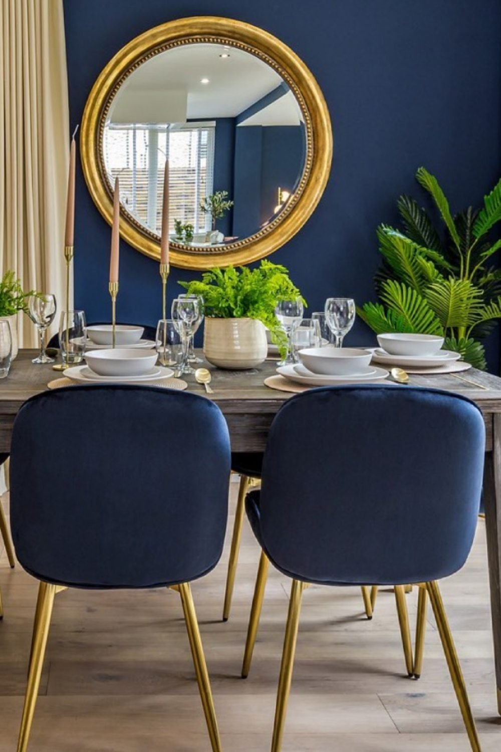 Minimalist design with navy chairs, gold legs, and round mirror.