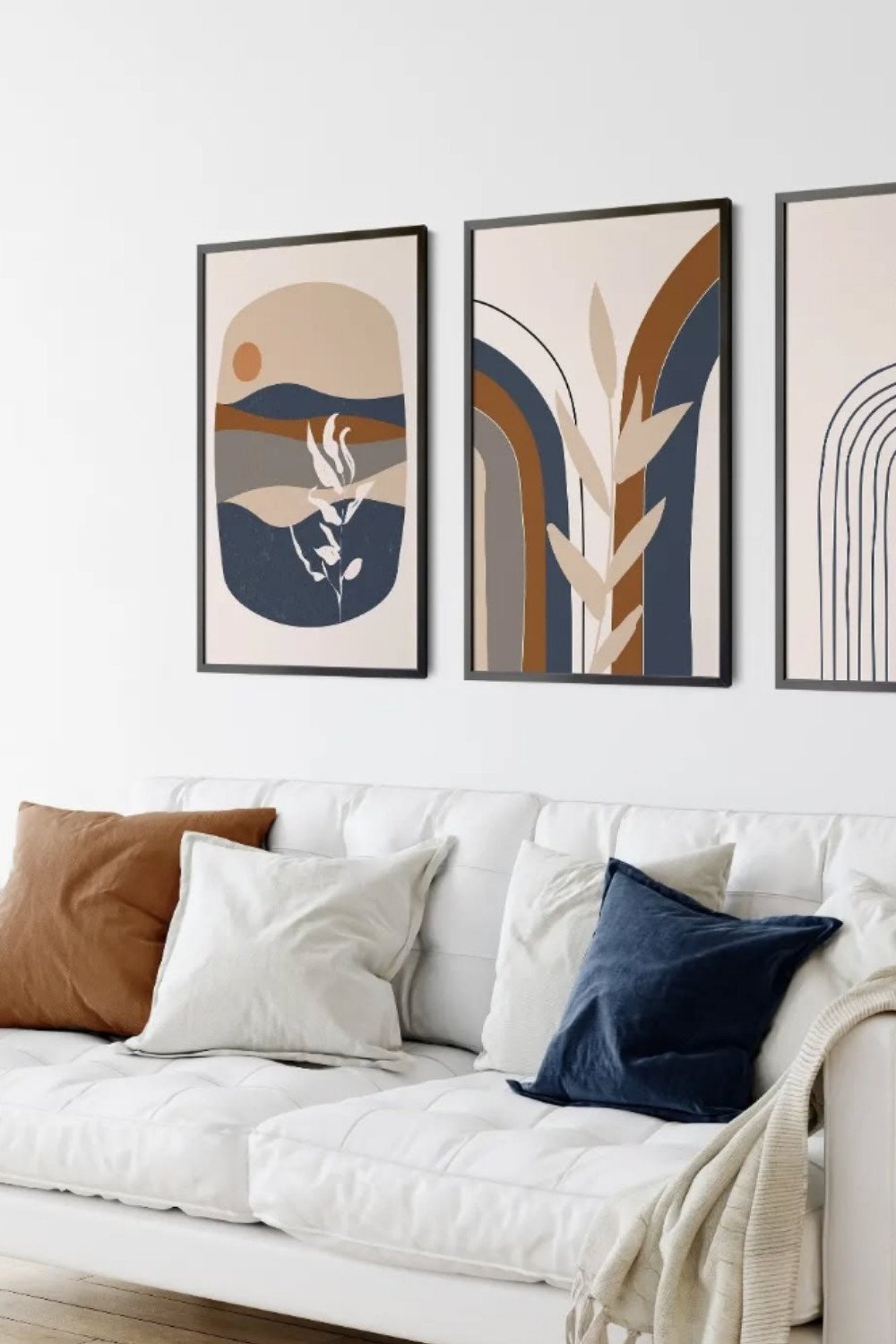 Clean white boho wall with abstract earthy-toned artwork and simple decor.