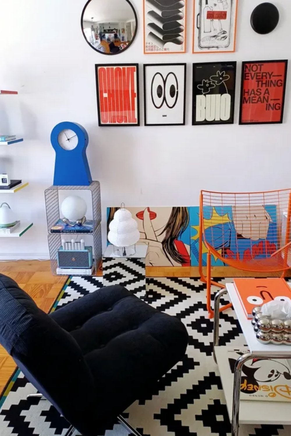 Playful gallery wall with bold graphics above patterned rug and bright furniture.