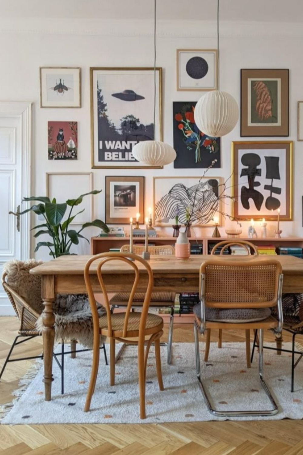 Dining room with refined gallery wall, natural wood table, and black-and-white prints.