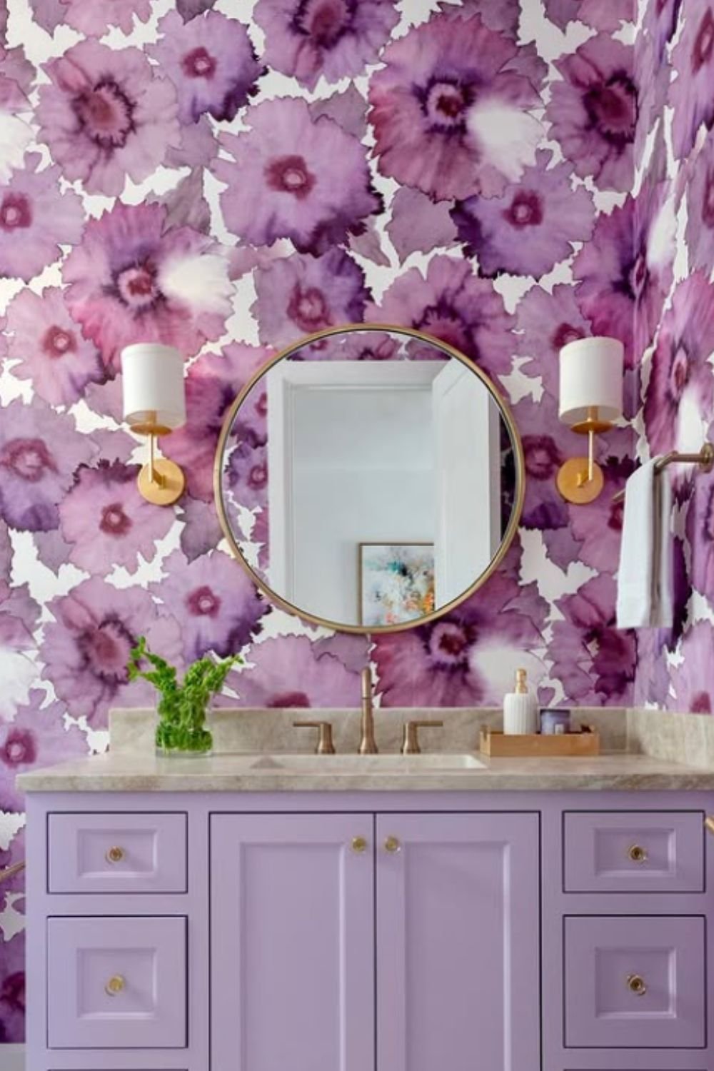 Bold bathroom with oversized purple floral wallpaper, lavender vanity, and brass lighting accents.