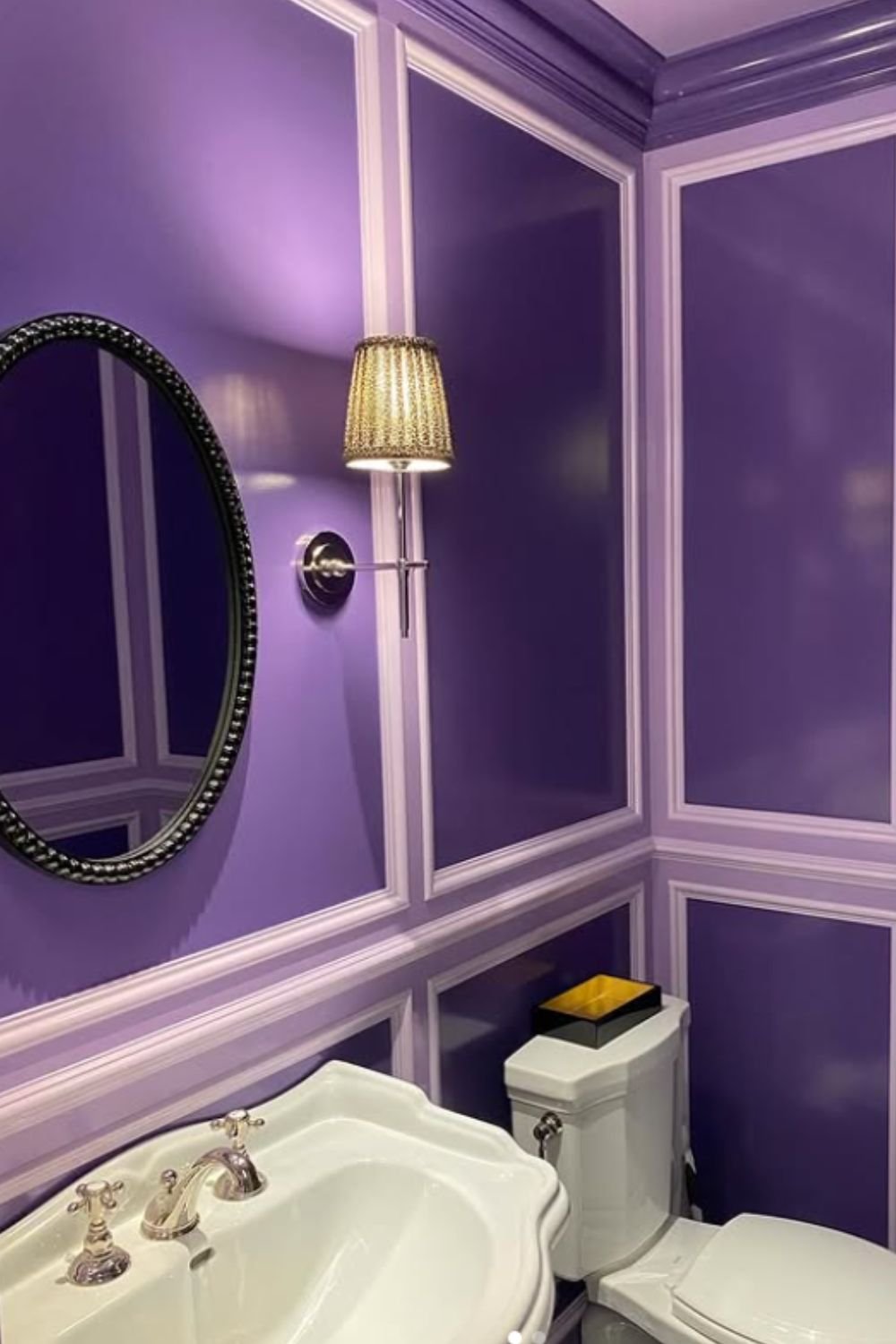 Elegant bathroom with deep purple paneled walls, gold accents, and soft lighting, showcasing refined purple bathroom ideas.
