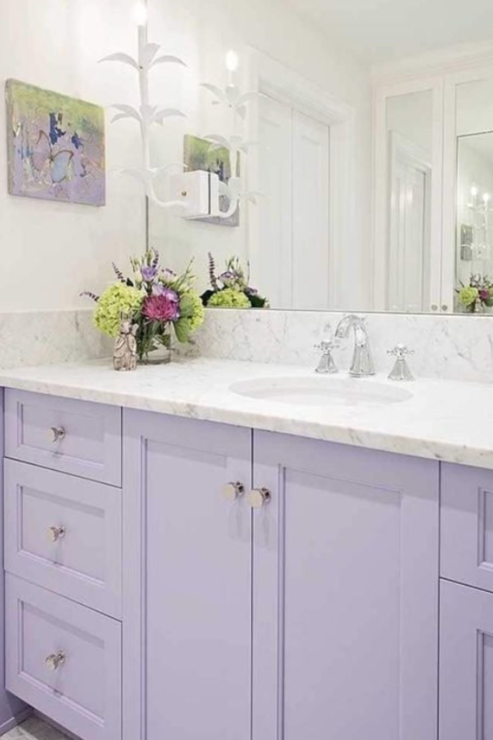 Bright bathroom with lavender cabinetry, marble countertop, and fresh floral accents for a light and airy vibe.