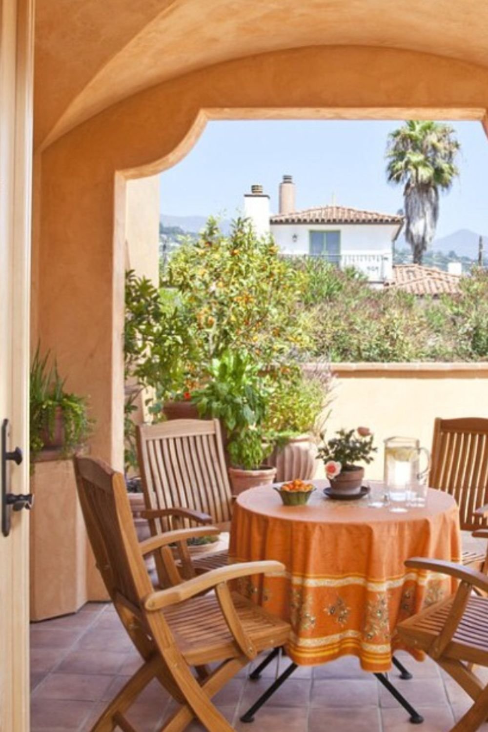Outdoor terrace with round table, orange tablecloth, and wooden chairs