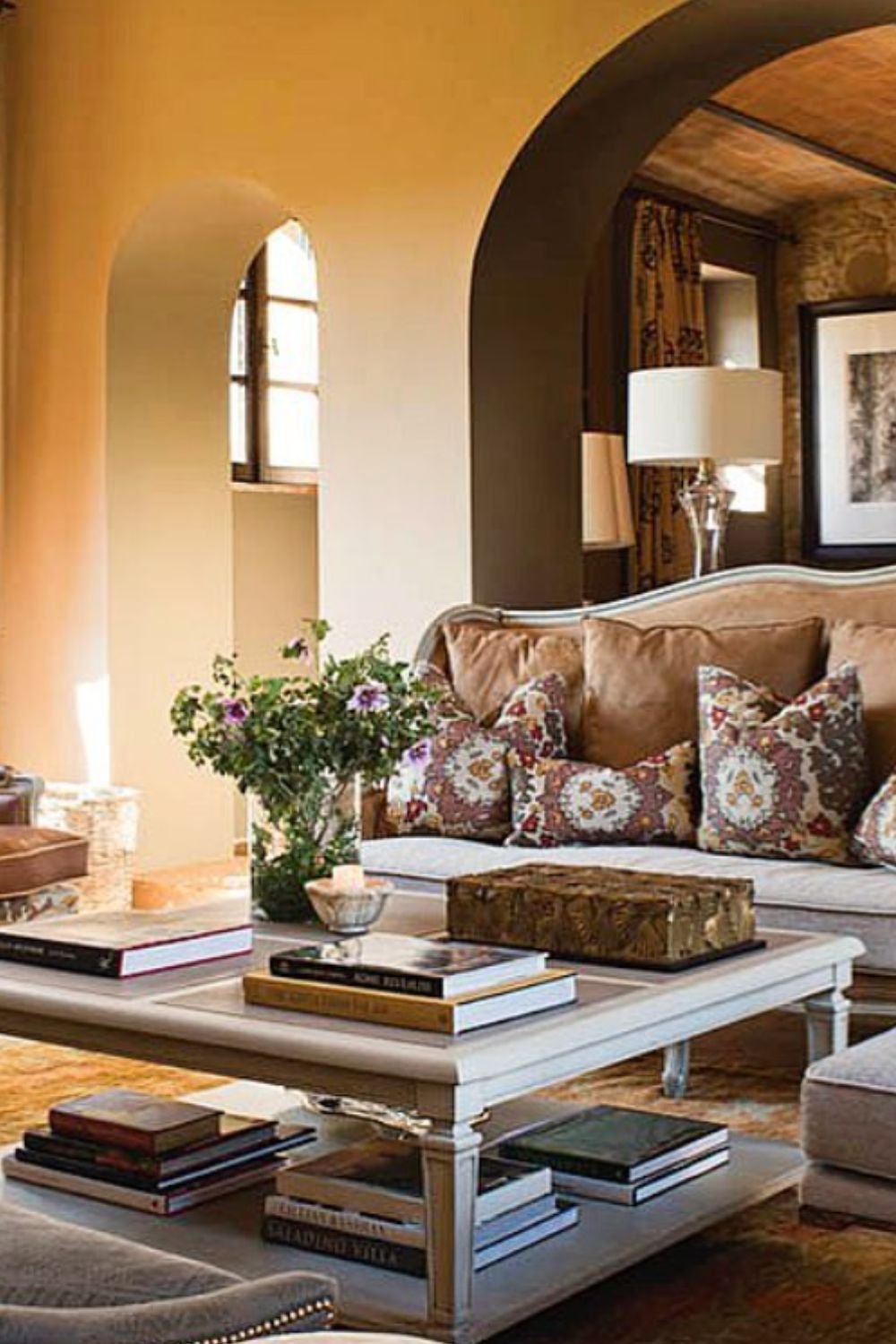 Warm living space with arched doorways, patterned sofa, and rustic coffee table – tuscan style home interior design