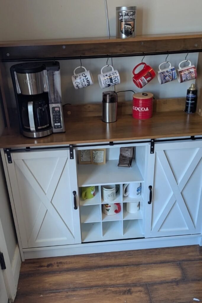 Rustic white coffee bar with barn-style doors, mugs, and wood counter.