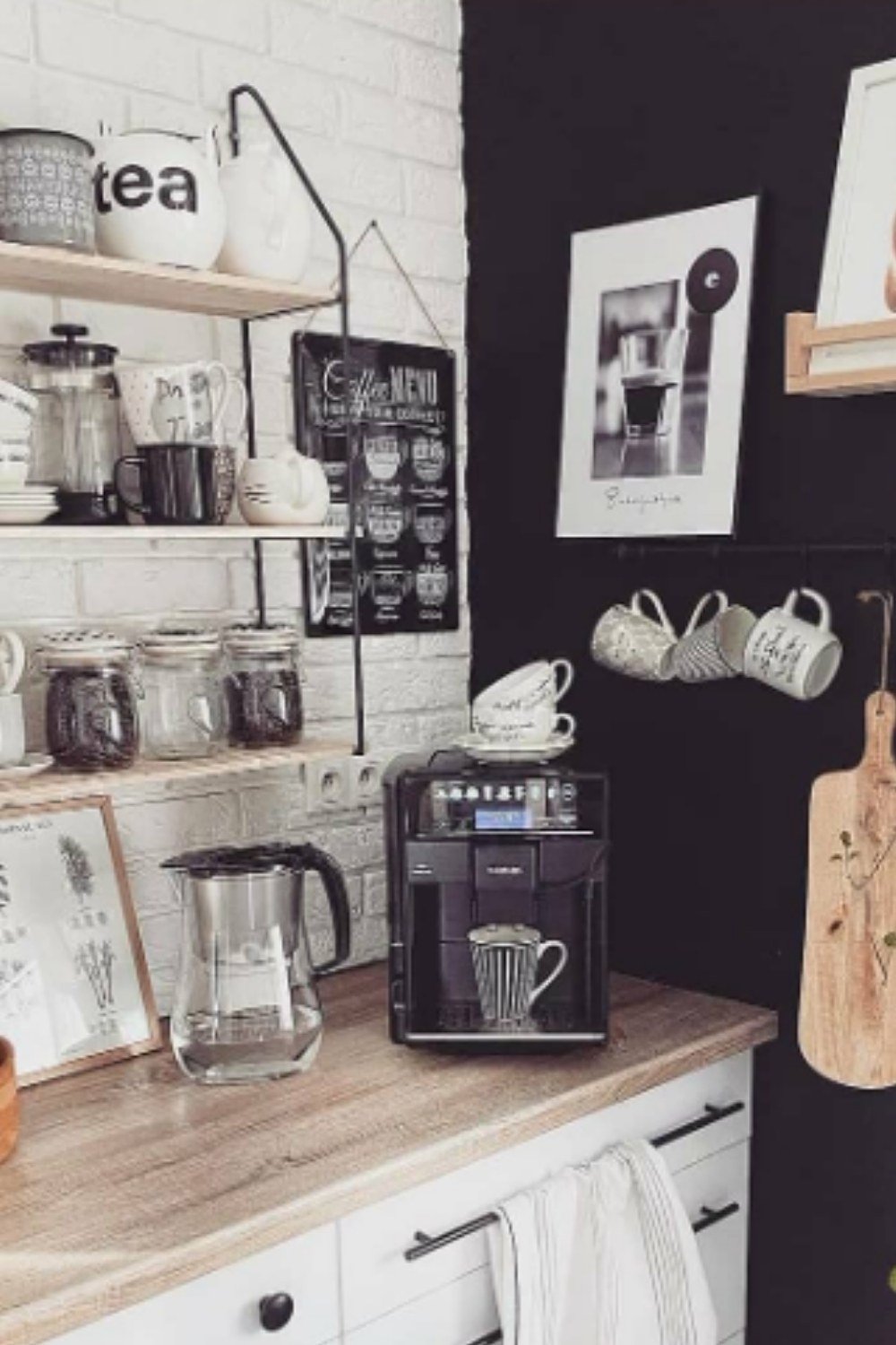 White coffee station with black accent wall, wood shelves, and jars.
