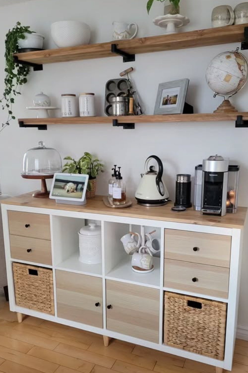 White cabinet coffee bar with woven baskets, open shelves, and framed art.