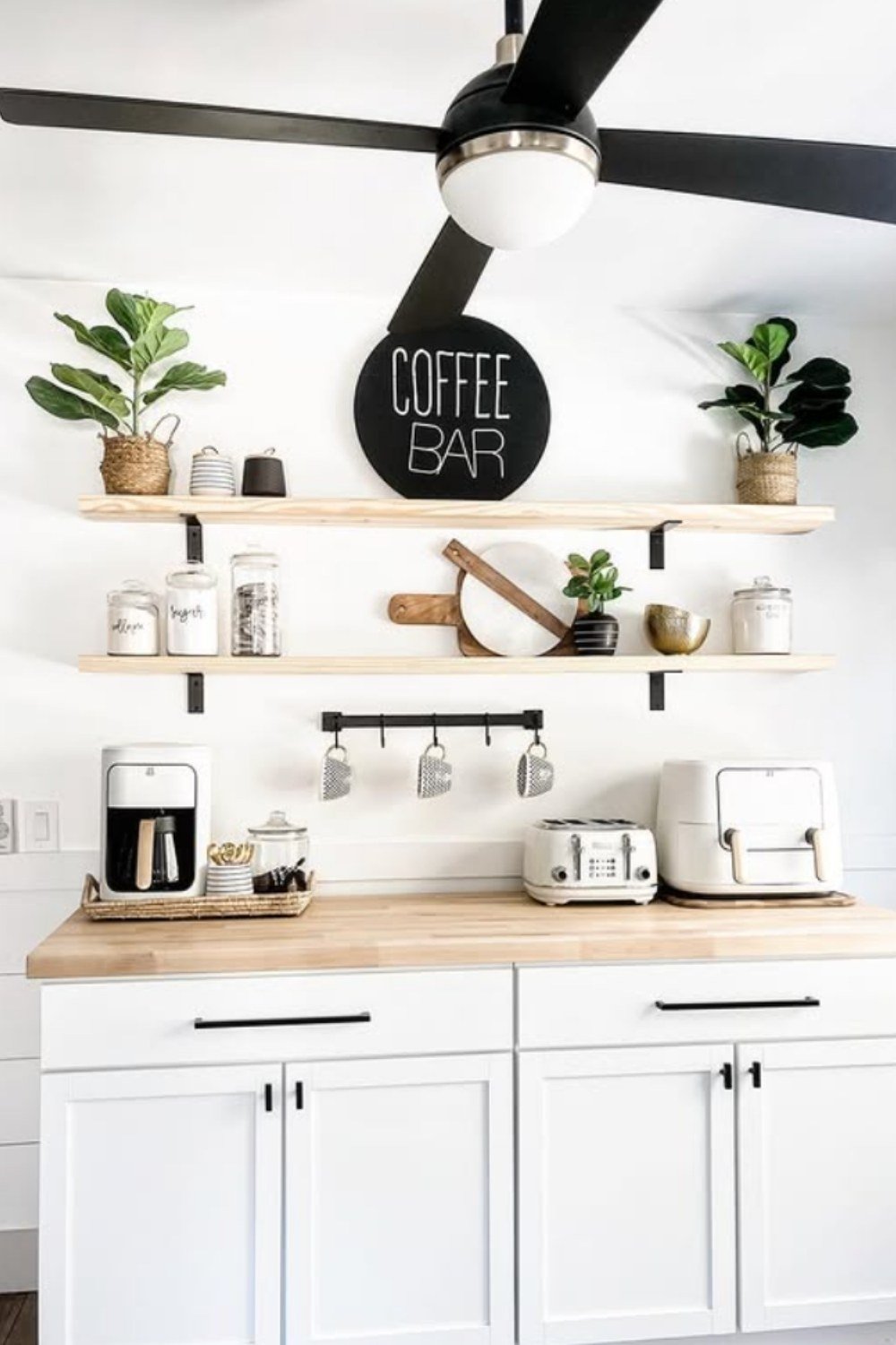 White coffee station with black circular “Coffee Bar” sign and greenery.