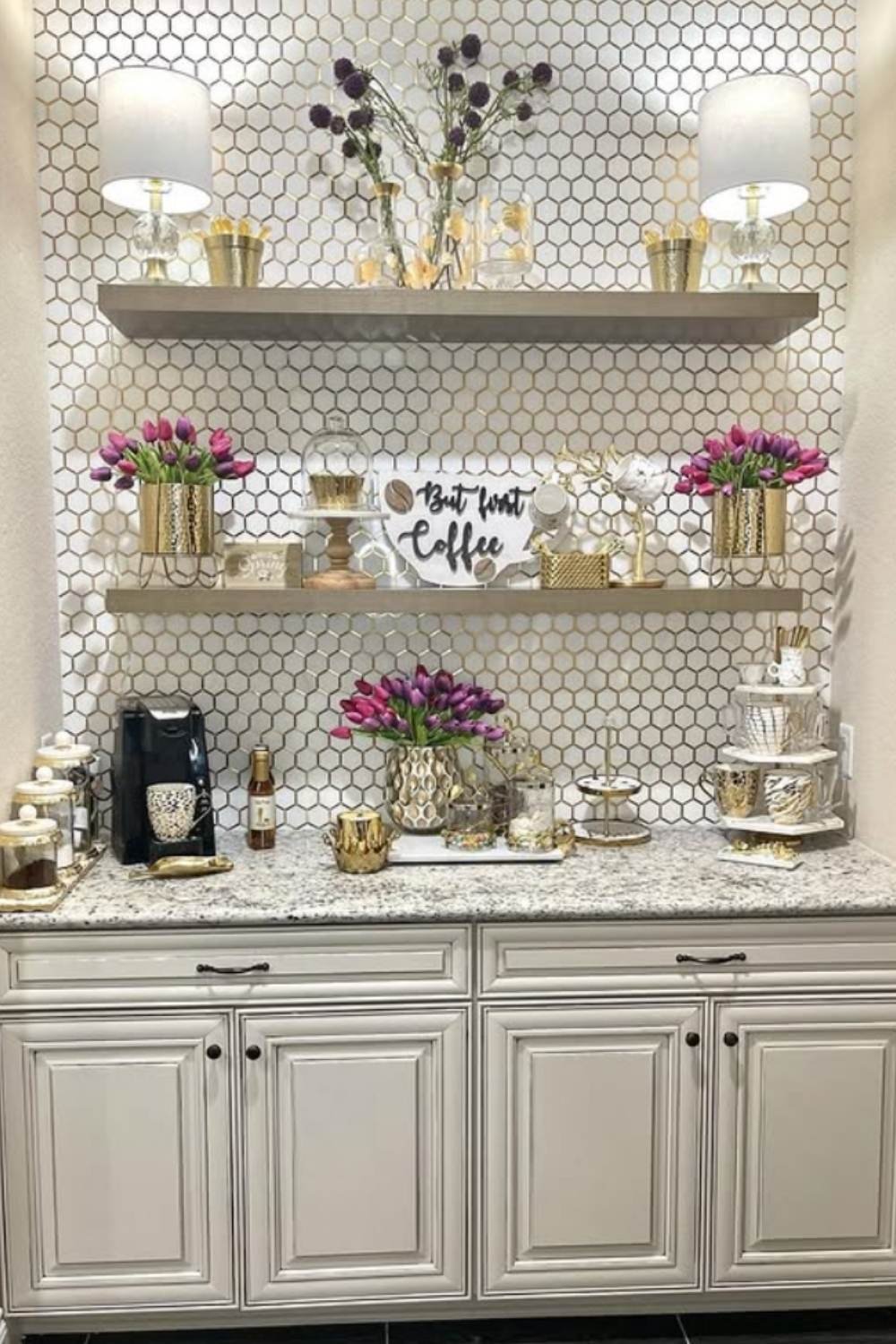 White coffee bar with honeycomb backsplash, flowers, and metallic accents.
