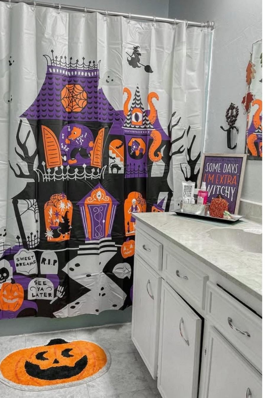 Colorful Halloween bathroom with cartoon ghost shower curtain, orange pumpkins, and festive wall decor.