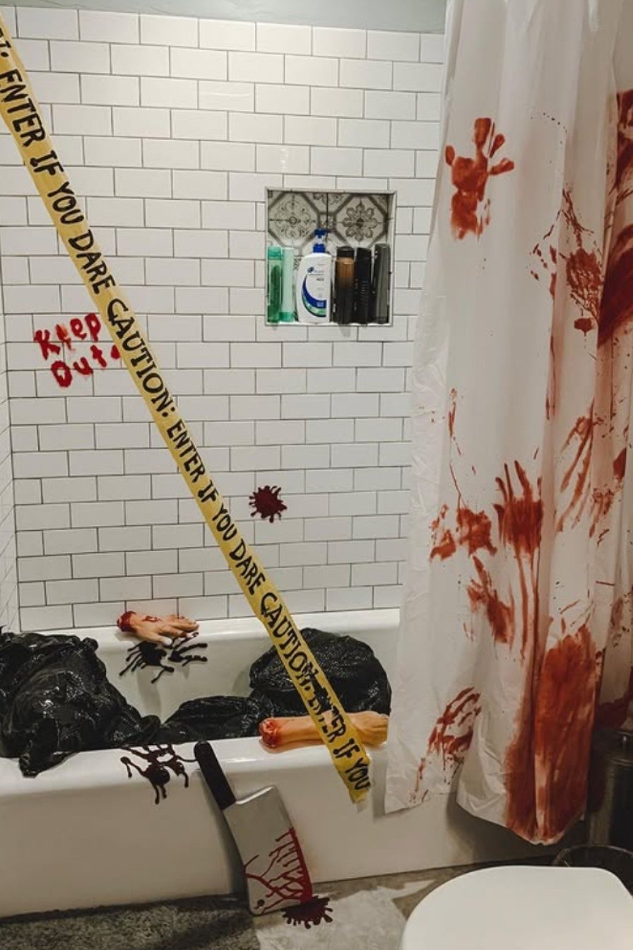 Bloody crime-scene-themed Halloween bathroom with caution tape, fake blood splatters, and eerie decor.