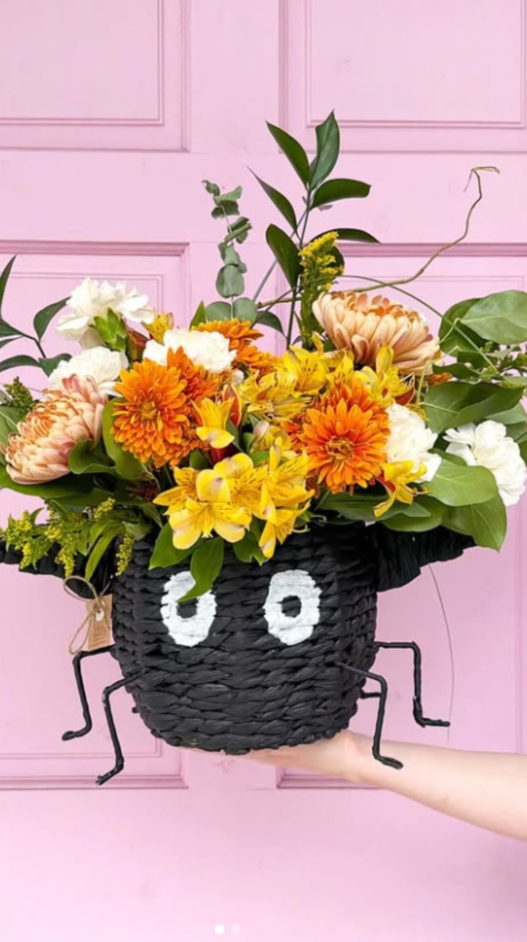 Halloween centerpiece with colorful flowers in a black spider-shaped basket