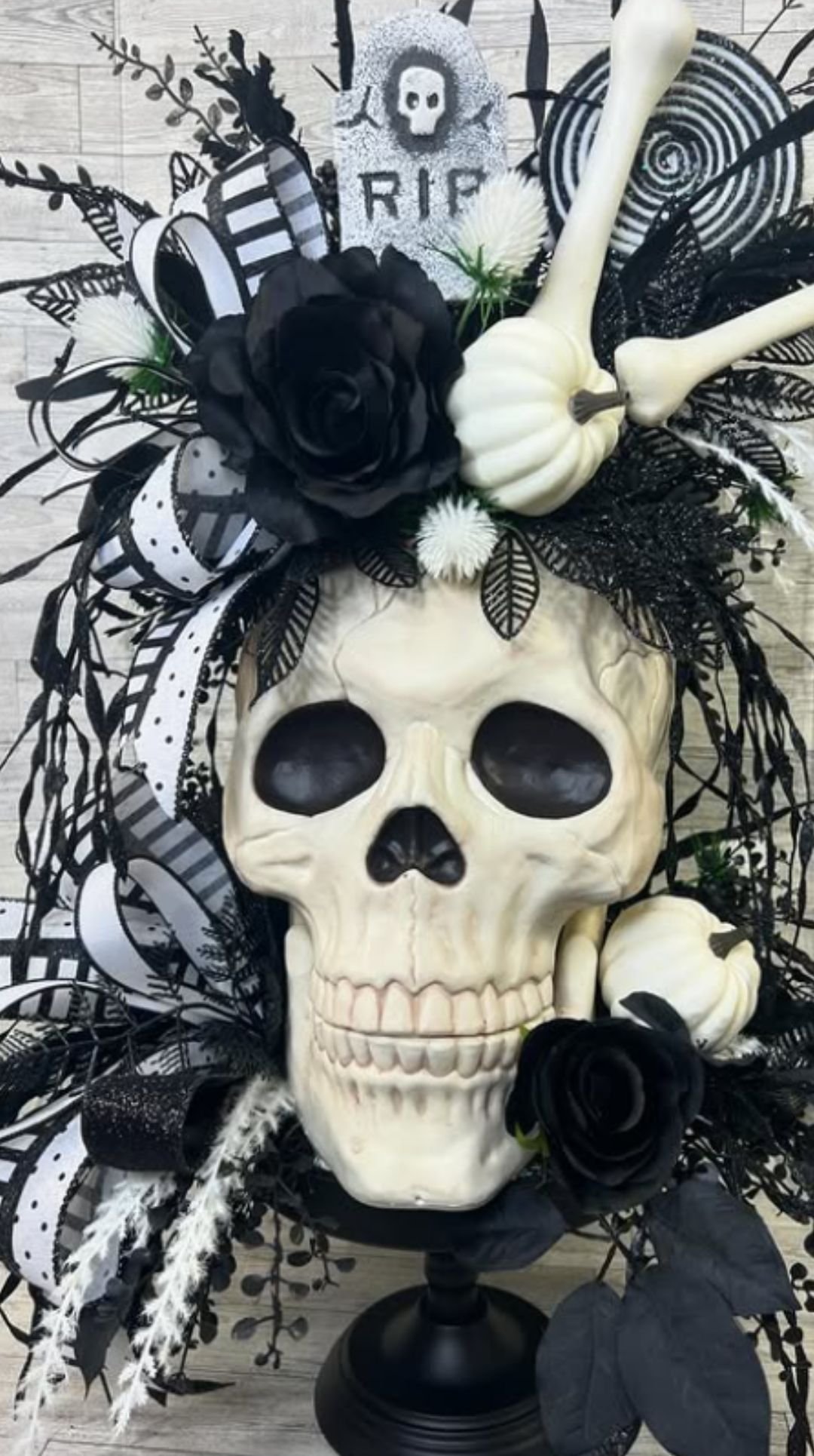 Halloween centerpiece with skull decorated with black roses, feathers, and gothic accents