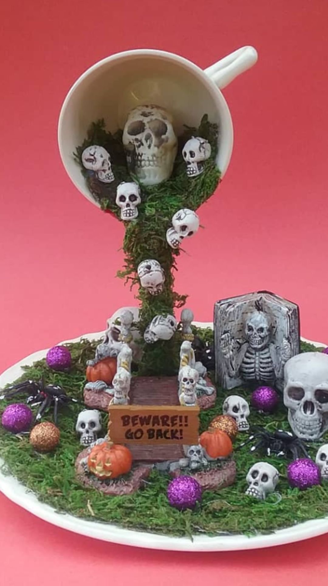 Floating teacup Halloween centerpiece pouring moss, skulls, and gravestones into a mini graveyard scene