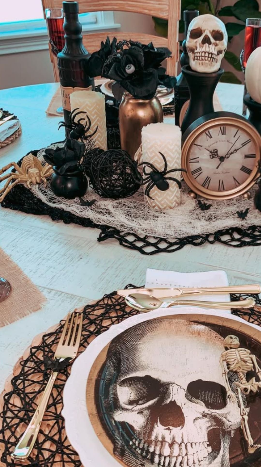 Halloween dining table centerpiece with skull plates, pumpkins, lace runner, and gothic accents