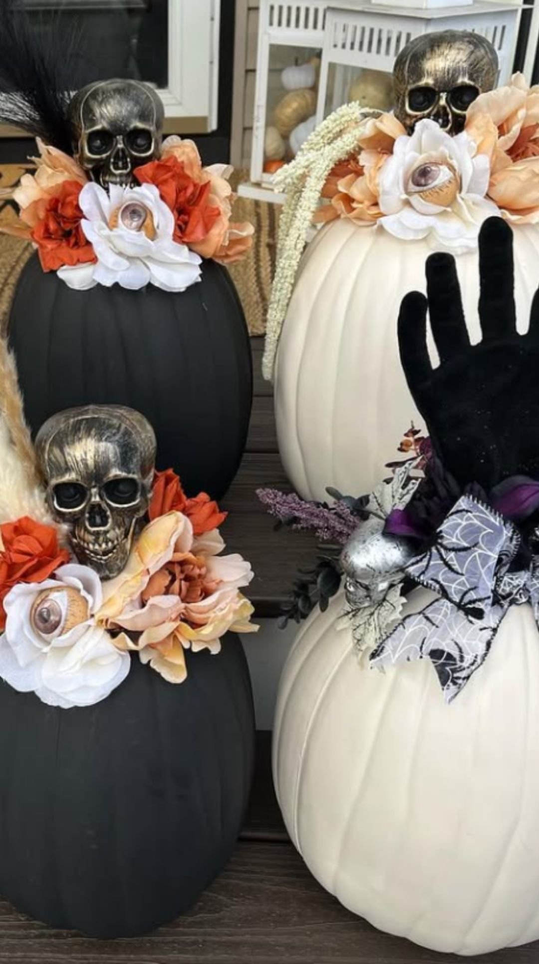 Halloween centerpiece with black and white pumpkins decorated with skulls, flowers, and creepy black hands