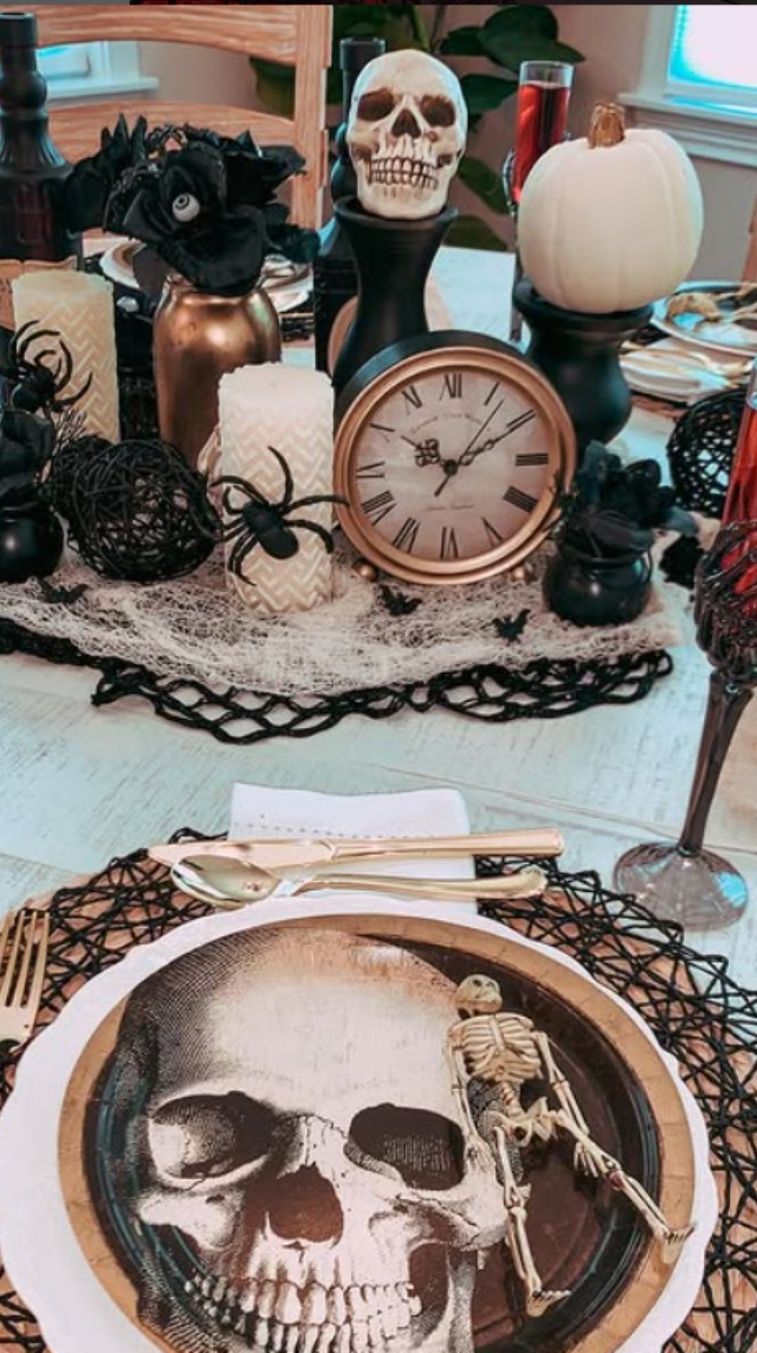 Dark Halloween tablescape with skull plates, pumpkins, and vintage clock