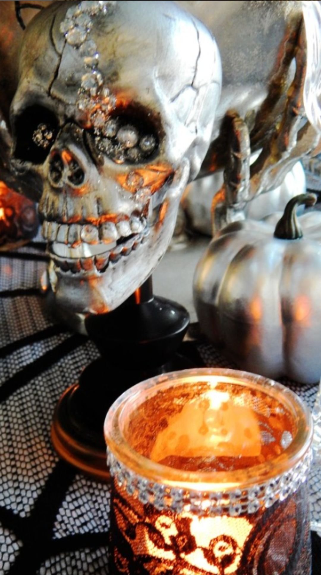 Glowing candle beside a metallic skull Halloween centerpiece
