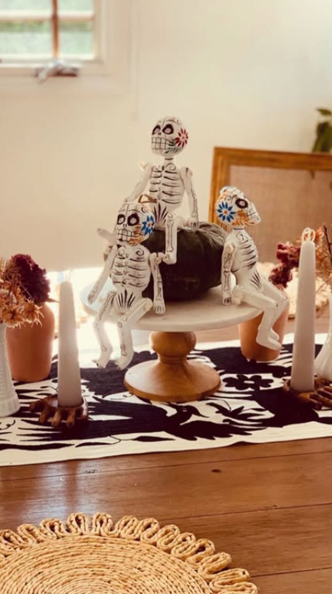 Playful skeleton figurines centerpiece with candles on a Halloween table
