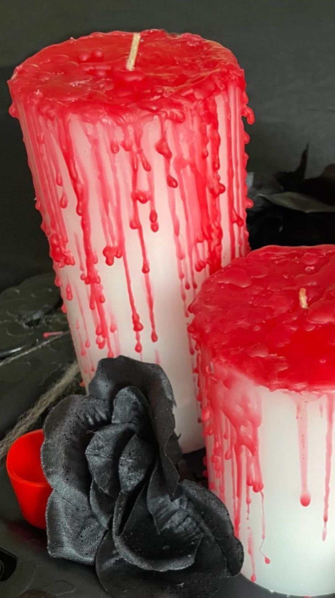 Halloween centerpiece with white candles dripping red wax and black roses