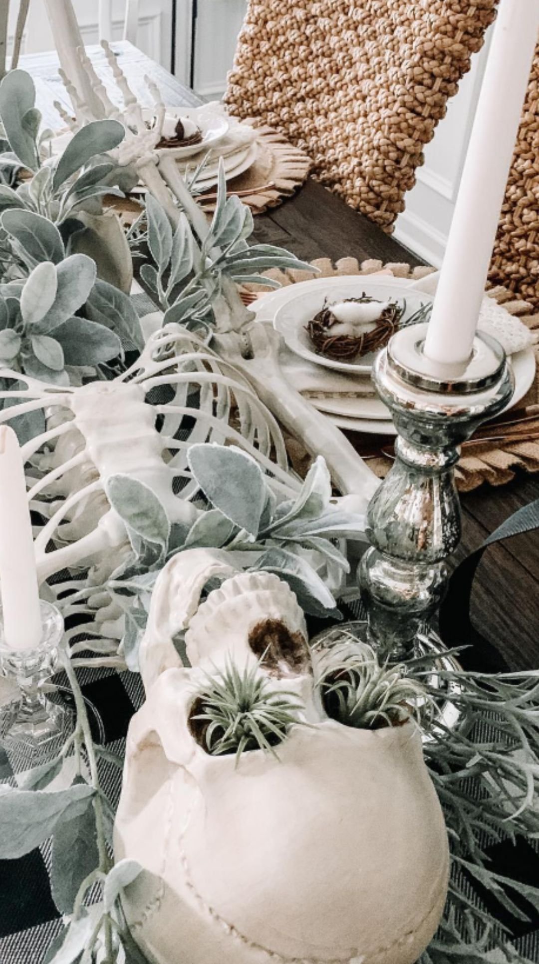 Halloween dining table centerpiece with skeleton ribcage, skulls, and greenery