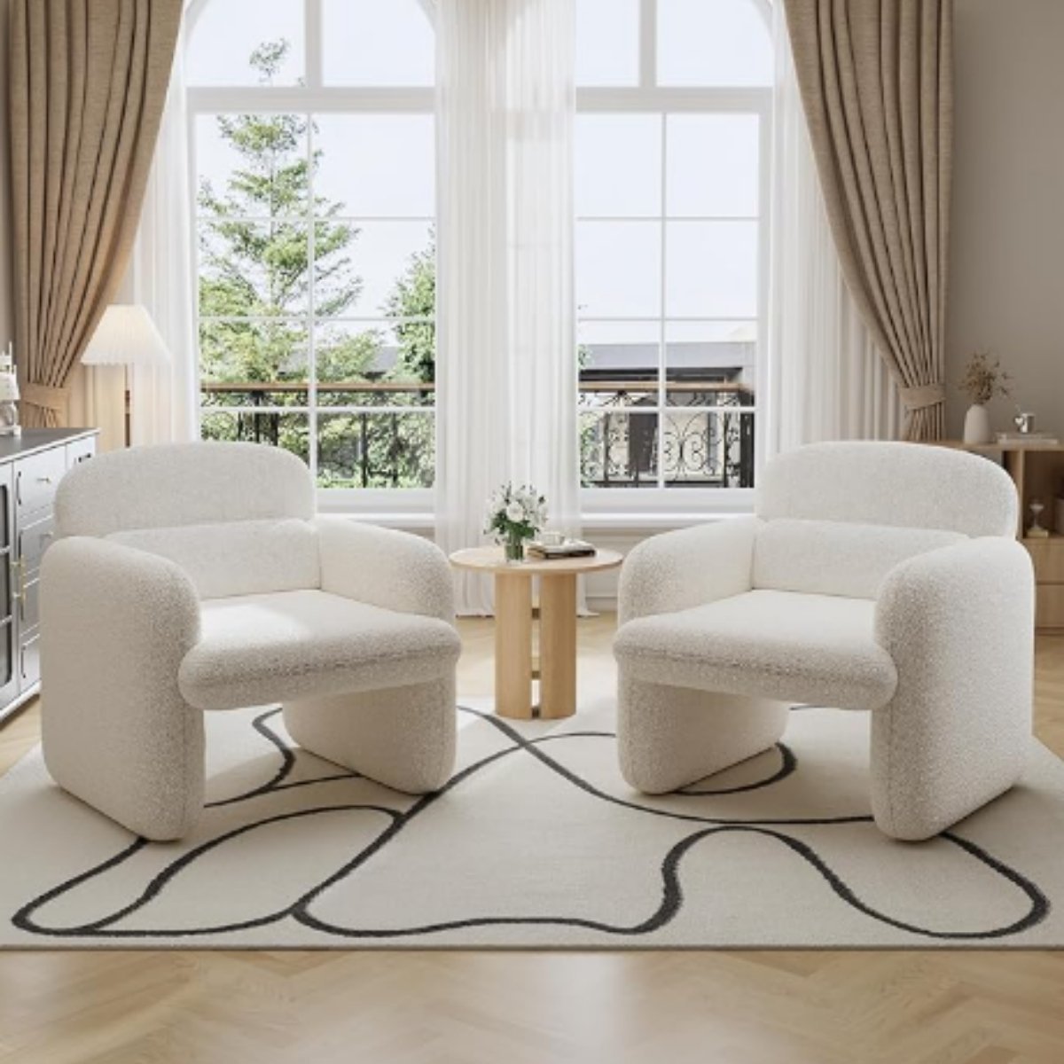 Soft white boucle accent chairs with modern rounded arms in a bright living room.
