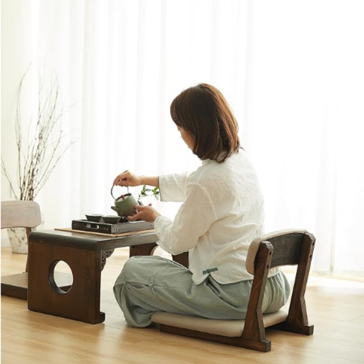 Japanese legless floor chair with wooden base and cushioned backrest for meditation or tea seating.